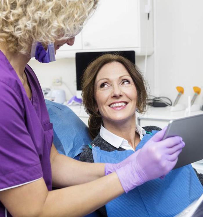 Female dental patient looking at teeth X-rays with dental hygienist