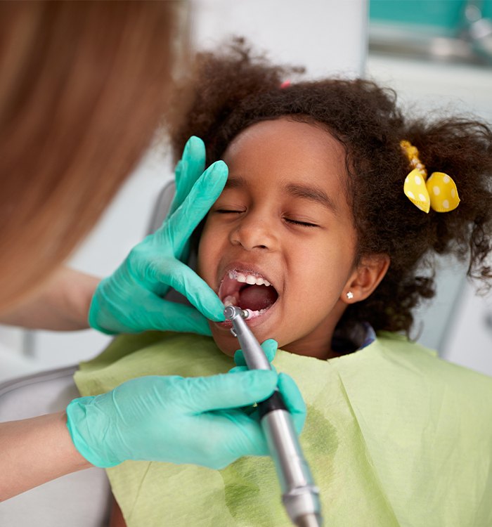 Child receiving dental checkup and teeth cleaning treatment