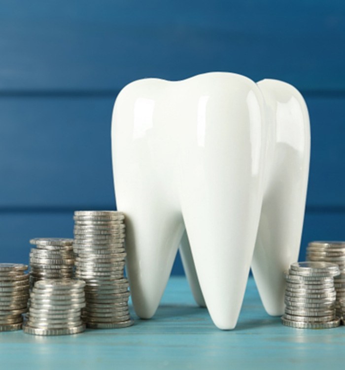 A large model tooth surrounded by silver coins