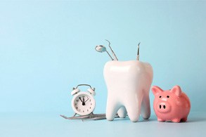 A tooth model with medical instruments and a piggy bank