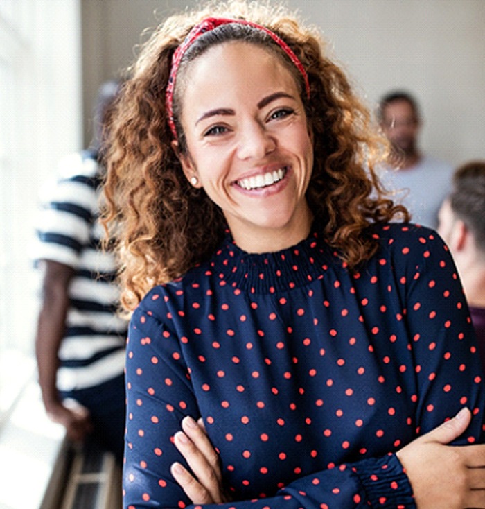 A young woman wearing a polka dot blouse and smiling