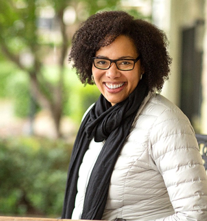 A middle-aged woman wearing a coat, scarf, and glasses showing off her beautifully restored smile