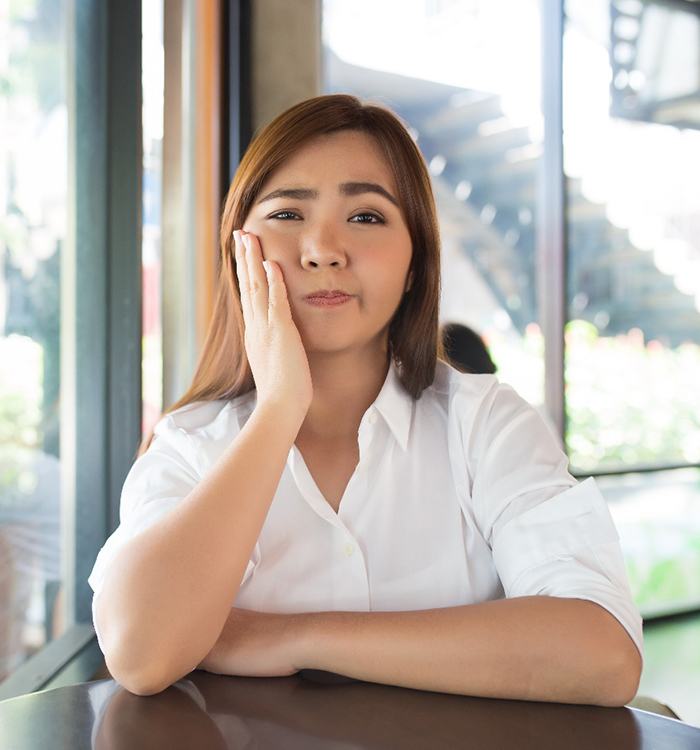 woman holding her cheek in pain