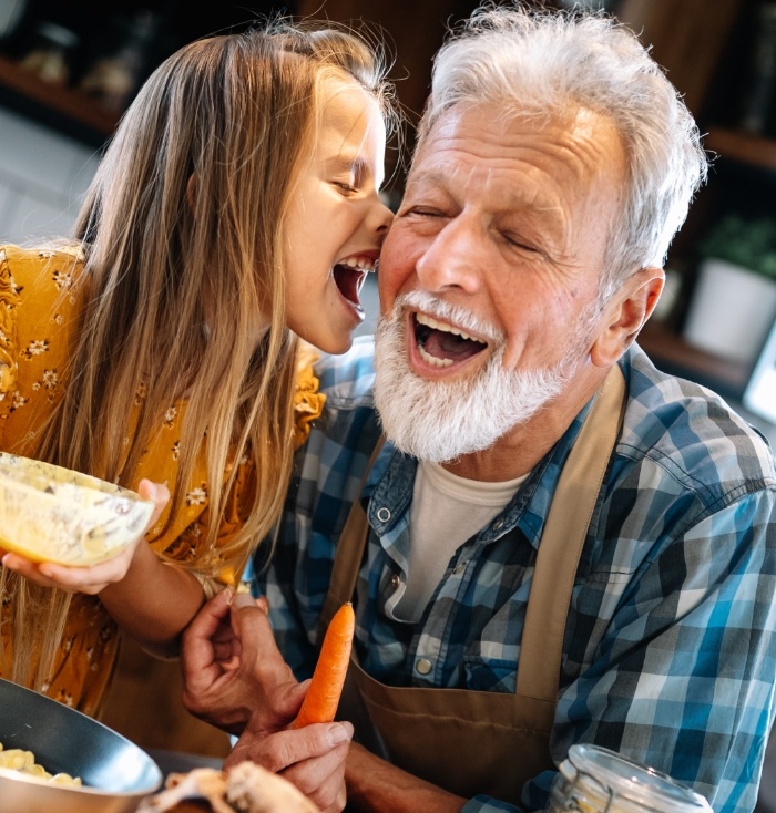 Older man smiling with his granddaughter