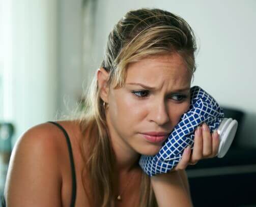 Woman holding ice pack to cheek