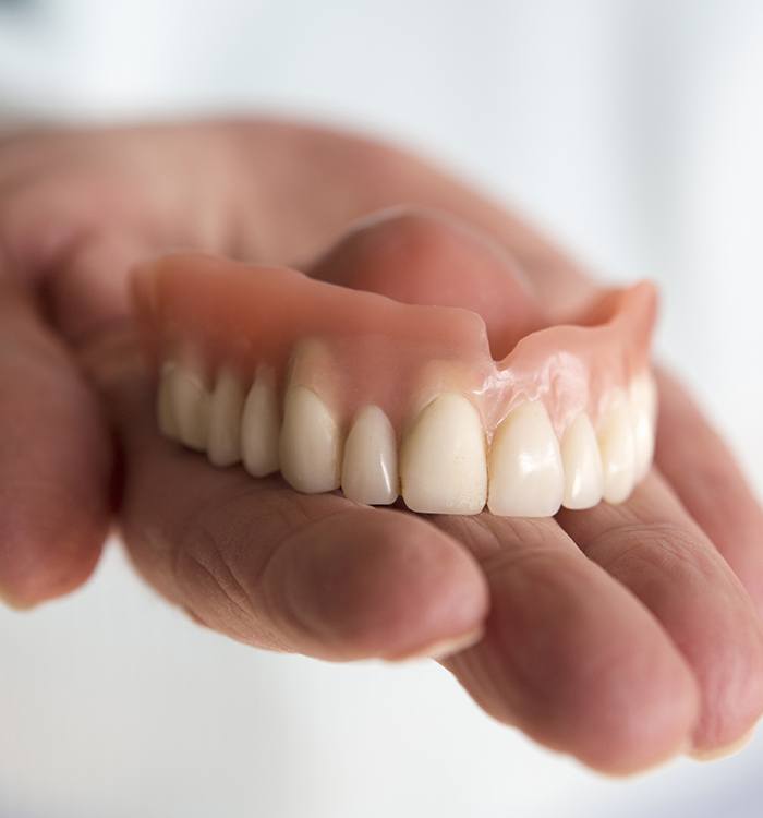 Hand holding full denture