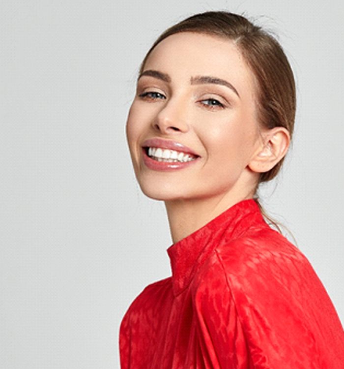 Woman in red shirt smiling confidently after KöR whitening treatment