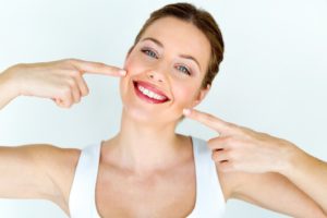 Woman pointing at her teeth after teeth whitening in Trumbull