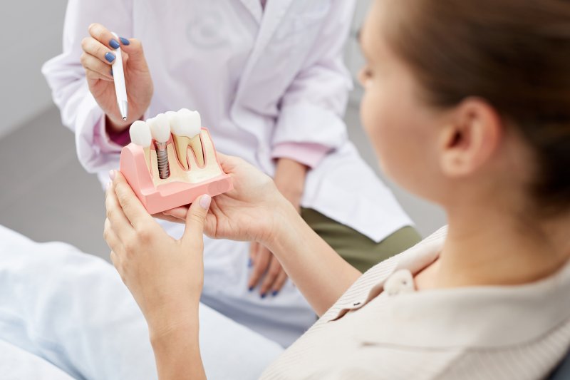 A dentist showing a dental implant model to a patient