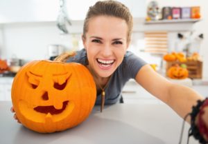 Smiling woman with carved pumpkin 